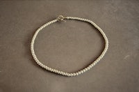 a white braided necklace with a gold clasp