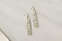a pair of silver dangling earrings on a table